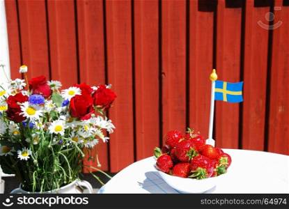 Summer decorated swedish table with strawberries, flowers and a swedish flag