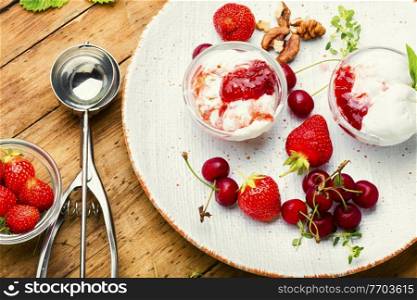 Summer dessert, ice cream with strawberries and cherries.Ice cream with berry jam on wooden table. Ice cream with berries and jam