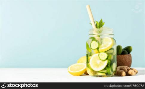 Summer detox and refreshing drink with cucumber, lemon, mint and ginger on sky blue background, banner, copy space. Detox infused water. Refreshing homemade cocktail summer drink, selective focus. Sunny day shadows