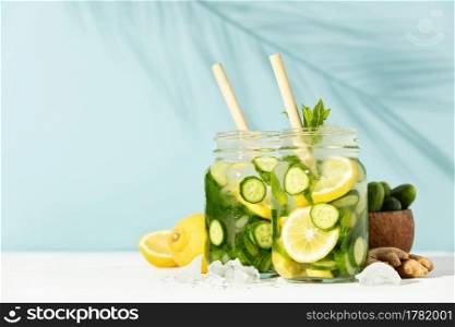 Summer detox and refreshing drinks with cucumber, lemon, mint and ginger on sky blue background. Sunny day shadows