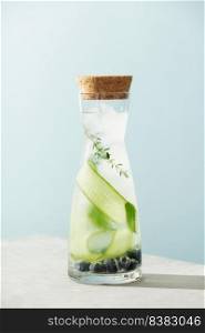 Summer drink in a bottle with cucumber, blackberry and rosemary on blue sky background