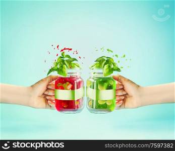 Summer drink in female hand. Red refreshing berries beverage in glass jar with green white branding mock up at sunny bight mint background. Summer mood. Blank Label at juice bottle