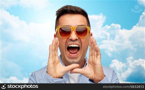 summer, emotions, communication and people concept - face of angry middle aged latin man in shirt and sunglasses shouting over blue sky and clouds background