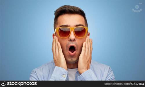 summer, emotions, style and people concept - face of scared or surprised middle aged latin man in shirt and sunglasses over blue background
