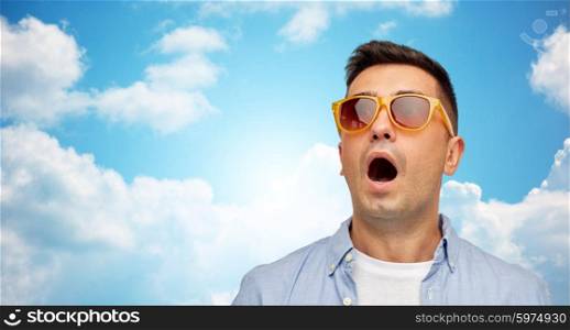 summer, emotions, style and people concept - face of scared or surprised middle aged latin man in shirt and sunglasses over blue sky and clouds background
