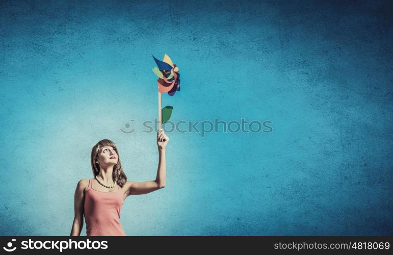 Summer energy. Happy young woman with windmill in hand