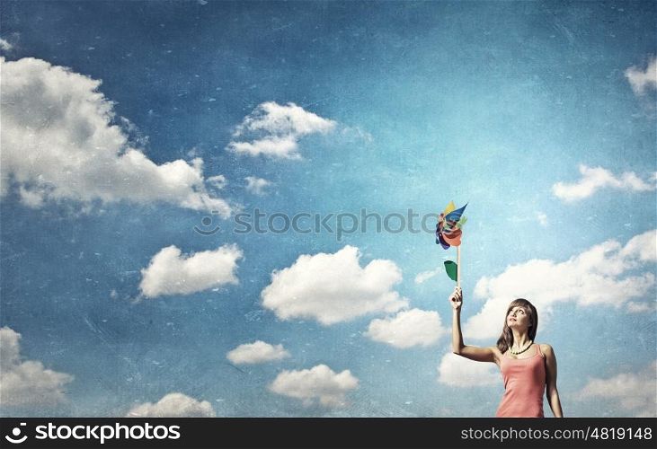 Summer energy. Happy young woman with windmill in hand