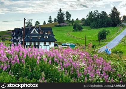 Summer evening mountain village with pink and white flowers in front (Gliczarow Gorny, Poland)