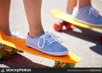 summer, extreme sport and people concept - close up of feet in shoes riding short modern cruiser skateboards on city street