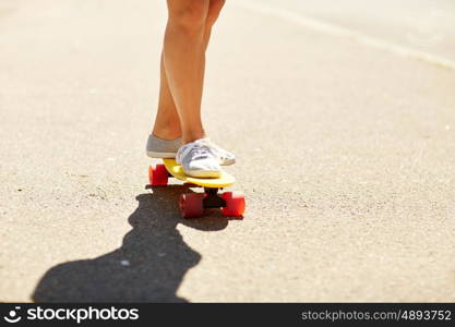 summer, extreme sport and people concept - legs of teenage girl or young woman riding skateboard on road