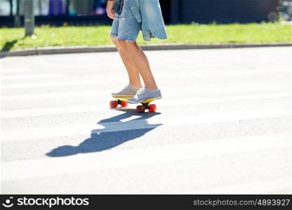 summer, extreme sport and people concept - teenage boy riding short modern cruiser skateboard on crosswalk in city