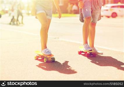 summer, extreme sport and people concept - teenage couple riding short modern cruiser skateboards on city street. teenage couple riding skateboards on city street