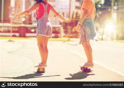 summer, extreme sport and people concept - teenage couple riding short modern cruiser skateboards on city street. teenage couple riding skateboards on city street