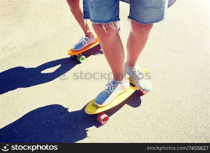 summer, extreme sport and people concept - teenage couple riding short modern cruiser skateboards on city road. teenage couple riding skateboards on city road