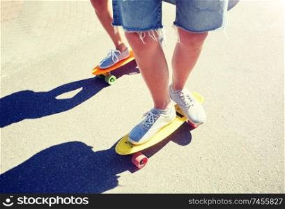 summer, extreme sport and people concept - teenage couple riding short modern cruiser skateboards on city road. teenage couple riding skateboards on city road