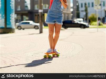 summer, extreme sport and people concept - teenage girl riding short modern cruiser skateboard on city street