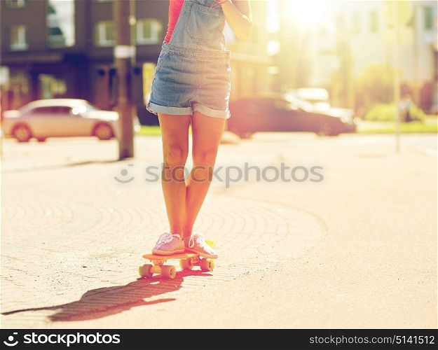 summer, extreme sport and people concept - teenage girl riding short modern cruiser skateboard on city street. teenage girl riding skateboard on city street