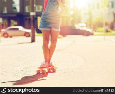 summer, extreme sport and people concept - teenage girl riding short modern cruiser skateboard on city street. teenage girl riding skateboard on city street