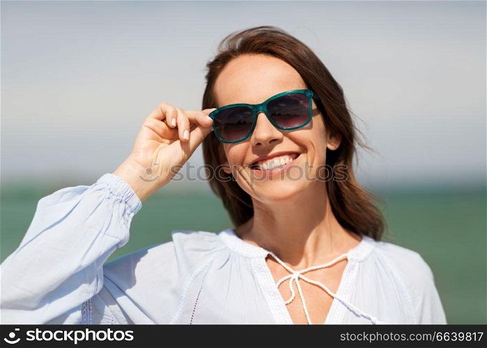 summer, eyewear and people concept - happy smiling woman in sunglasses on beach. happy smiling woman in sunglasses on summer beach