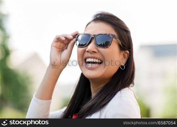 summer, eyewear and people concept - portrait of happy smiling young woman in sunglasses outdoors. portrait of young woman in sunglasses outdoors