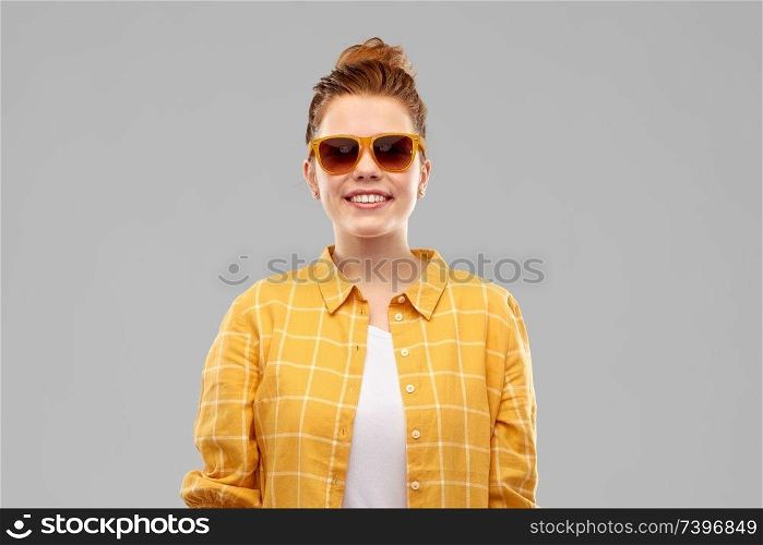summer, eyewear and people concept - smiling red haired teenage girl in sunglasses and yellow checkered shirt over grey background. smiling red haired teenage girl in sunglasses