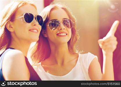 summer, fashion, accessories and people concept - happy women in sunglasses pointing finger in city. happy women in sunglasses pointing finger outdoors