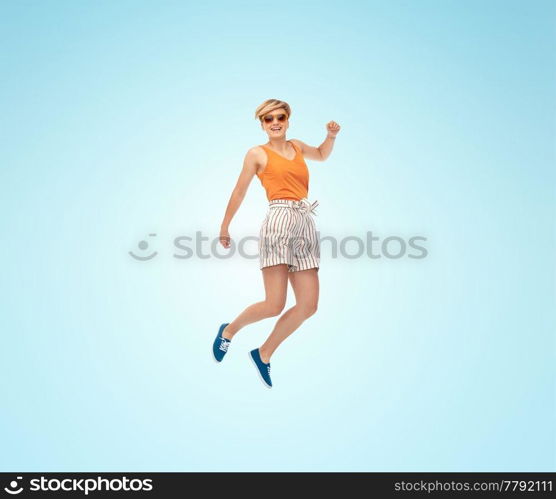 summer, fashion and people concept - happy teenage girl in sunglasses jumping over blue background. happy teenage girl in sunglasses jumping