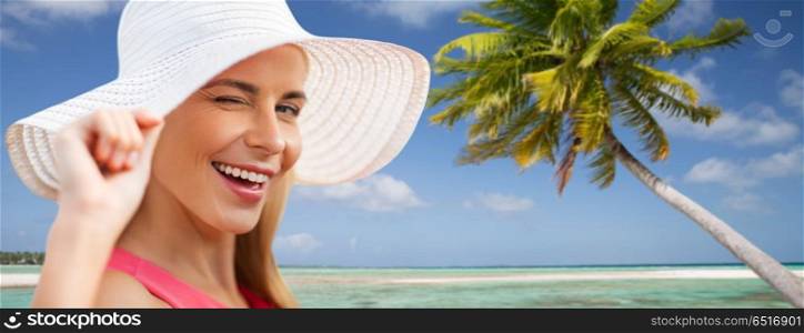 summer, fashion and people concept - portrait of beautiful smiling woman in sun hat over tropical beach background in french polynesia. beautiful smiling woman in sun hat on beach. beautiful smiling woman in sun hat on beach