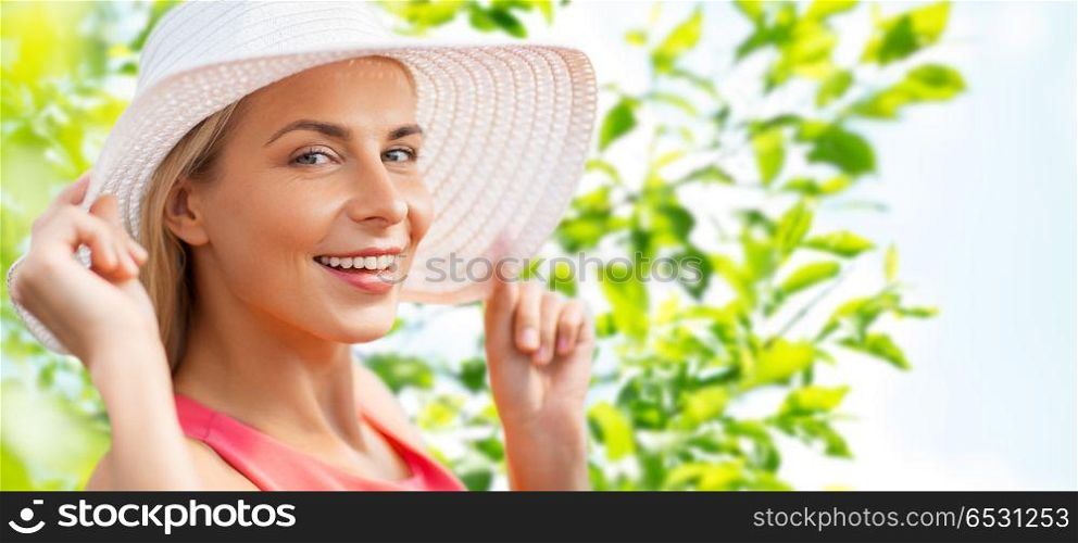 summer, fashion and people concept - portrait of beautiful smiling woman in sun hat over green natural background. portrait of beautiful smiling woman in sun hat. portrait of beautiful smiling woman in sun hat