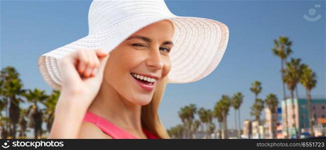 summer, fashion and people concept - portrait of beautiful smiling woman in sun hat over venice beach background in california. l smiling woman in sun hat over venice beach. l smiling woman in sun hat over venice beach