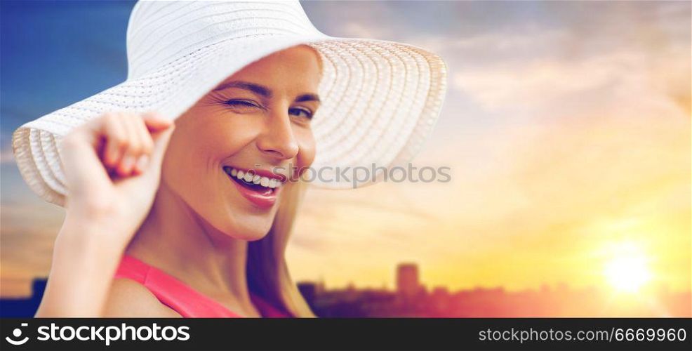 summer, fashion and people concept - portrait of beautiful smiling woman in sun hat over city sunset background. beautiful smiling woman in sun hat over sunset. beautiful smiling woman in sun hat over sunset