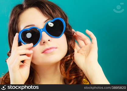 Summer fashion eyes protection concept. Closeup girl long curly hair in blue heart shaped sunglasses