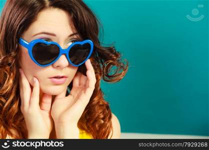 Summer fashion eyes protection concept. Closeup girl long curly hair in blue heart shaped sunglasses