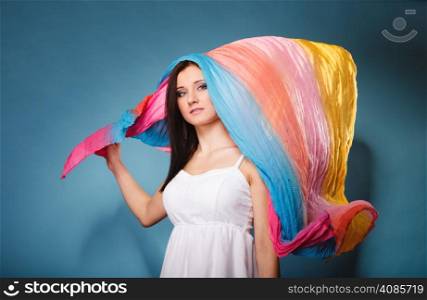 Summer fashion. Pretty young woman fashionable sensual girl with multicolored flying shawl on blue background