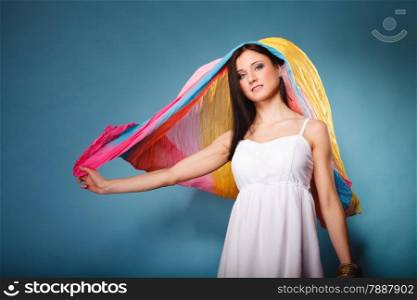 Summer fashion. Pretty young woman fashionable sensual girl with multicolored flying shawl on blue background
