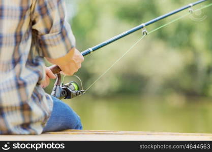 Summer fishing. Close up of guy sitting on bridge and fishing