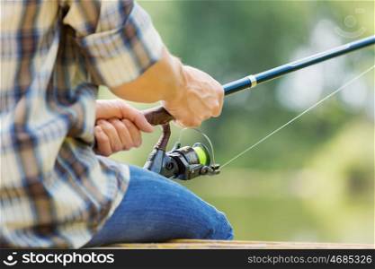 Summer fishing. Close up of guy sitting on bridge and fishing