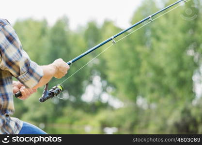 Summer fishing. Close up of guy sitting on bridge and fishing