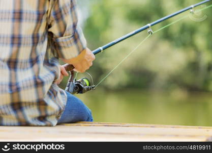 Summer fishing. Close up of guy sitting on bridge and fishing