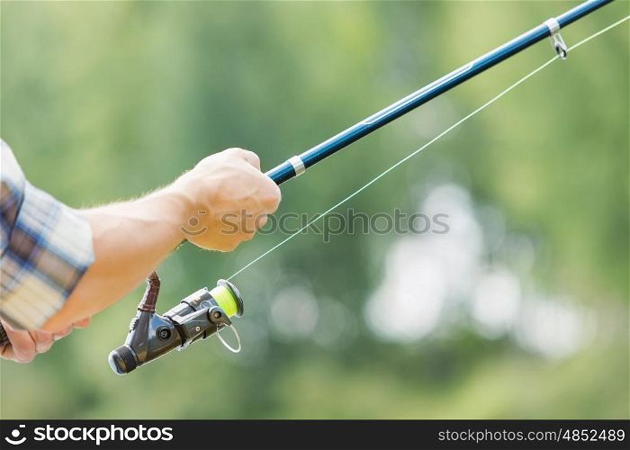 Summer fishing. Close up of guy sitting on bridge and fishing