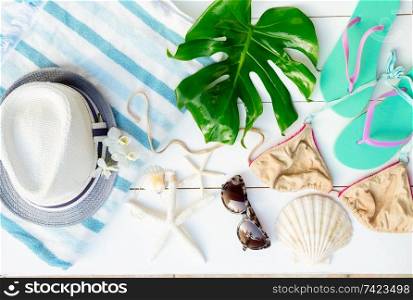 Summer flat lay scenery with beach accessories on white wooden background planks. Summer flat lay scenery with swimsuit