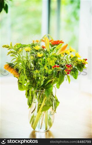 Summer flowers bunch mit sunflowers in glass vase at window