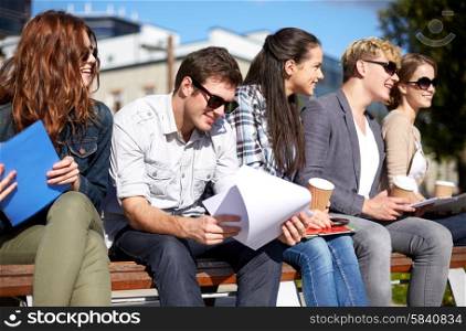 summer, friendship, education and teenage concept - group of happy students with notebooks learning and drinking coffee at campus