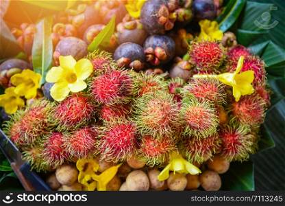 Summer fruit with rambutan longkong mangosteen in the basket on banana leaf background with flowers / Thai fruit
