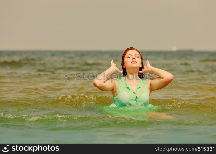 Summer fun, recreation outside concept. Redhead adult woman playing in water during summertime, having great time and smiling joyfully. Redhead woman playing in water during summertime