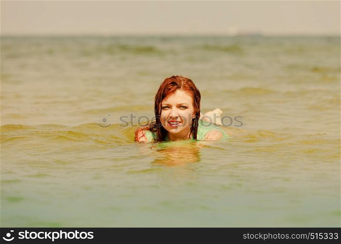 Summer fun, recreation outside concept. Redhead adult woman playing in water during summertime, having great time and smiling joyfully. Redhead woman playing in water during summertime
