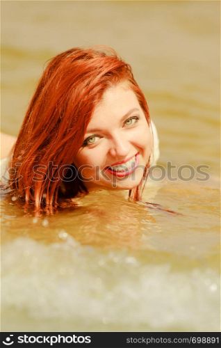 Summer fun, recreation outside concept. Redhead adult woman posing in water during summertime, having great time.. Redhead woman posing in water during summertime
