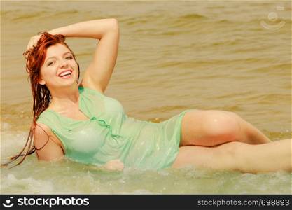 Summer fun, recreation outside concept. Redhead adult woman posing in water during summertime, having great time.. Redhead woman posing in water during summertime