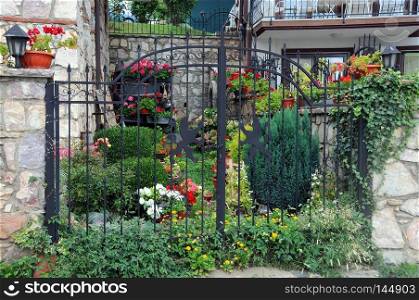 Summer garden behind black metal gate