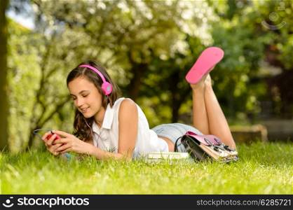 Summer girl lying on grass listen to music pink headphones